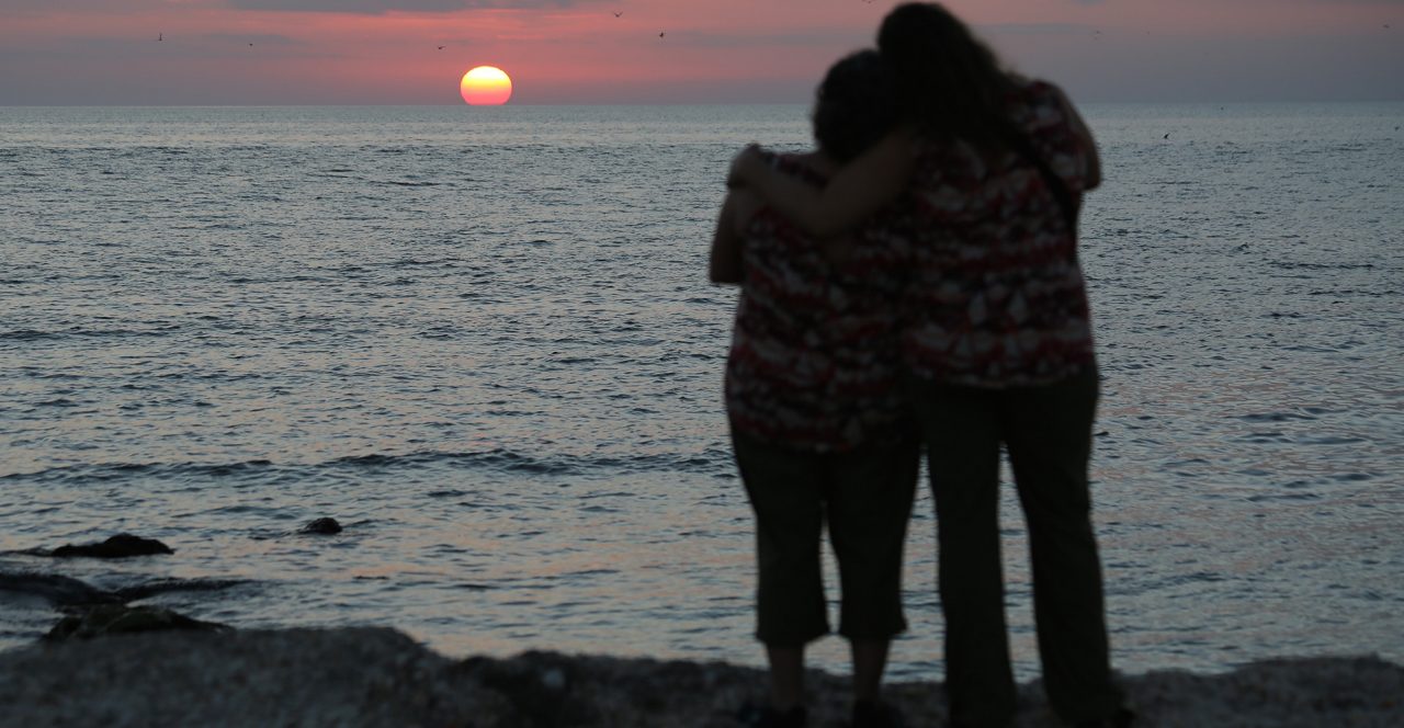 Two people hug as the sun sets.